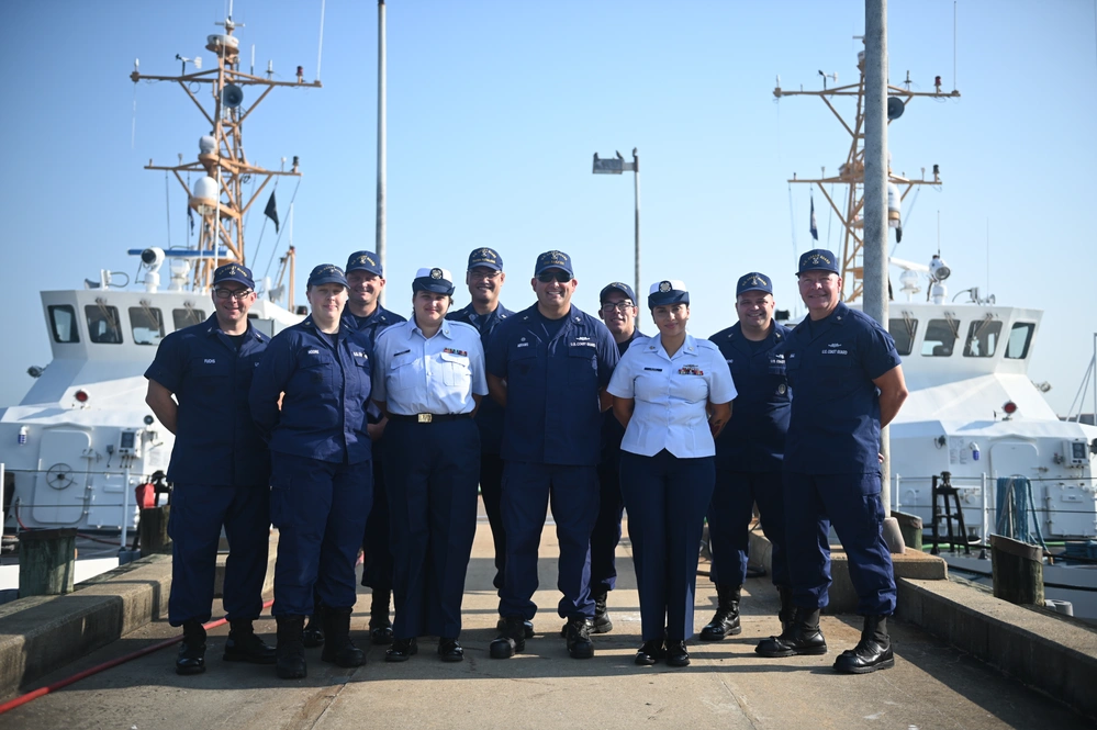 Petty Officer 2nd Class Gabriella Alongi and Petty Officer 1st Class Jennaya Allen pose for a group photo with various members of culinary specialist leadership from Coast Guard Headquarters following Allen's advancement ceremony at Coast Guard Station Little Creek in Virginia Beach, Virginia, Aug. 26, 2024. Allen was relieved as the primary culinary specialist aboard the USCGC Sailfish (WPB-87356) by her own sister, CS2 Alongi, as CS1 Allen makes her way to the USCGC Frederick Hatch (WPC 1143) in Guam. (U.S. Coast Guard Photo by Petty Officer 2nd Class Ryan L. Noel)