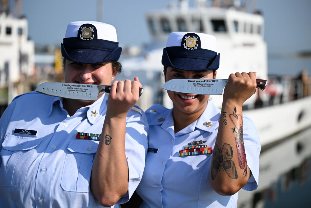 Petty Officer 2nd Class Gabriella Alongi and Petty Officer 1st Class Jennaya Allen pose with their newly acquired knives that read, “Thank you and YES CHEF!” which was gifted to them by Master Chief Petty Officer James Swenson, the rating force master chief for culinary specialists, during an advancement ceremony at Coast Guard Station Little Creek in Virginia Beach, Virginia, Aug. 26, 2024. The knives are an acknowledgment from the master chief of their achievements as culinary specialists and is a unique gift within the rating. (U.S. Coast Guard Photo by Petty Officer 2nd Class Ryan L. Noel)