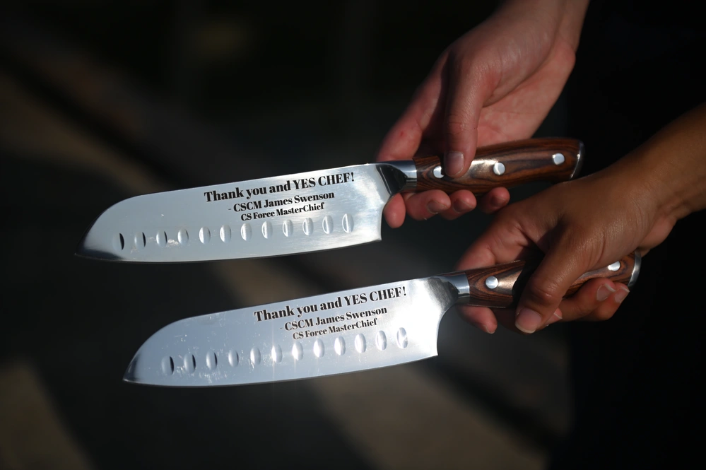 Petty Officer 2nd Class Gabriella Alongi and Petty Officer 1st Class Jennaya Allen present their newly acquired knives that read, “Thank you and YES CHEF!” which was gifted to them by Master Chief Petty Officer James Swenson, the rating force master chief for culinary specialists, during an advancement ceremony at Coast Guard Station Little Creek in Virginia Beach, Virginia, Aug. 26, 2024. Allen was relieved as the primary culinary specialist aboard the USCGC Sailfish (WPB-87356) by her own sister, CS2 Alongi, as CS1 Allen makes her way to the USCGC Frederick Hatch (WPC 1143) in Guam. (U.S. Coast Guard Photo by Petty Officer 2nd Class Ryan L. Noel)