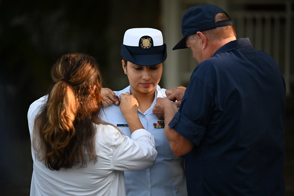 Petty Officer 1st Class Jennaya Allen is pinned to first class by her mother and local auxiliary mentor Tom Lappe, during her advancement ceremony at Coast Guard Station Little Creek in Virginia Beach, Virginia, Aug. 26, 2024. Allen will was relieved by her own sister, CS2 Alongi, as she transfers to the USCGC Frederick Hatch (WPC 1143) in Guam. (U.S. Coast Guard Photo by Petty Officer 2nd Class Ryan L. Noel)