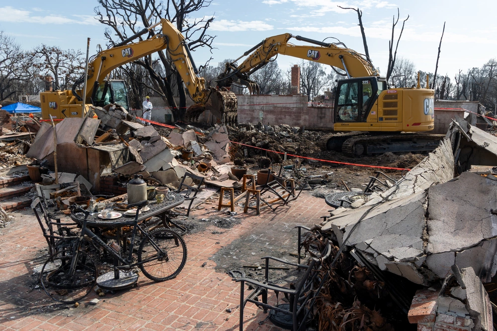 Heavy equipment operators work to remove fire-damaged debris from a residential property in Pacific Palisades, California, on Feb. 19, 2025.