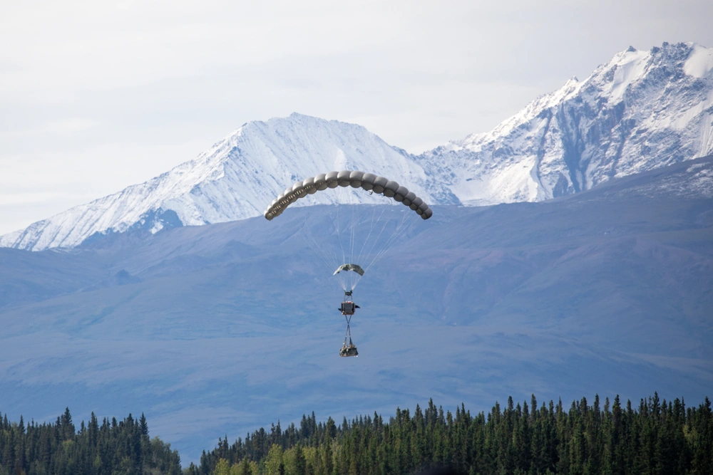 A parachute bundle descends during an experimental drop as a part of Arctic Edge 25 (AE25) near Tok, Alaska, Aug. 12, 2025. The experimental resupply system demonstrated how the military can sustain operations in environments where global positioning systems are denied or disrupted. AE25 is a North American Aerospace Defense Command and U.S. Northern Command-led homeland defense exercise designed to improve readiness, demonstrate capabilities, and enhance Joint and Allied Force interoperability in the Arctic.