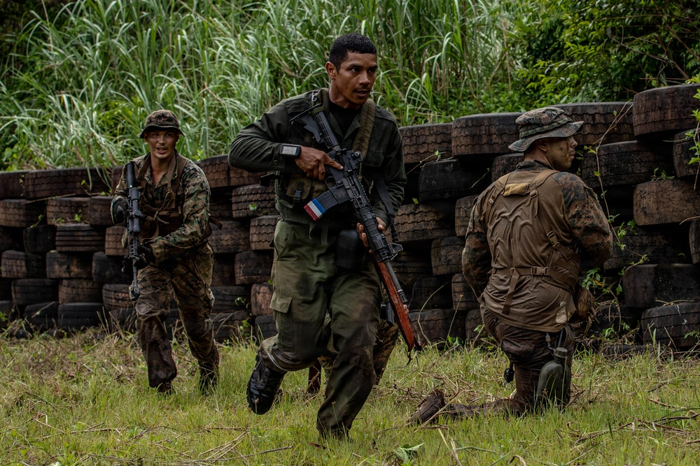 Soldiers with rifles conduct drills in the jungle.