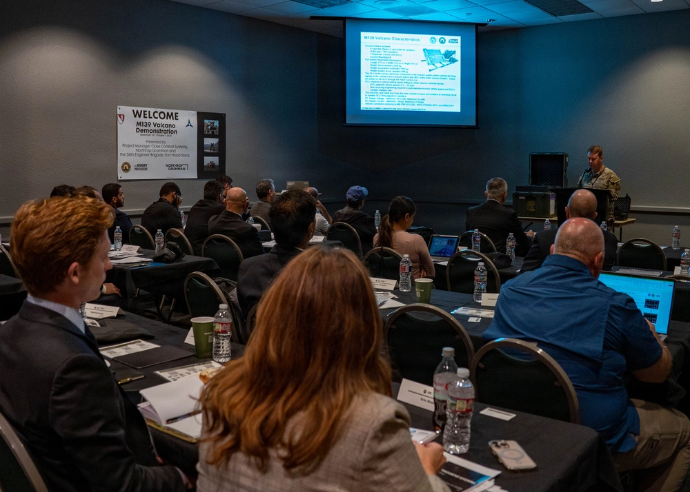 Attendees listen to a detailed presentation on the M139 Volcano system’s characteristics and operational capabilities during a formal briefing session.