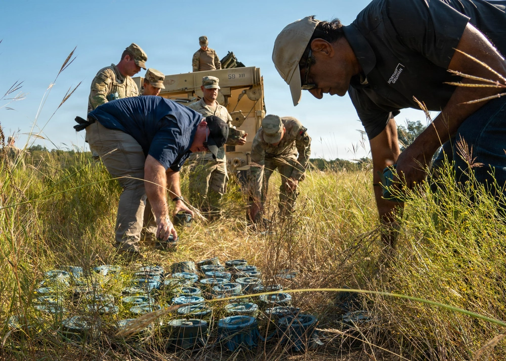 Personnel inspect and organize deployed M139 inert munitions (M88R) to evaluate their placement and functionality in the field.